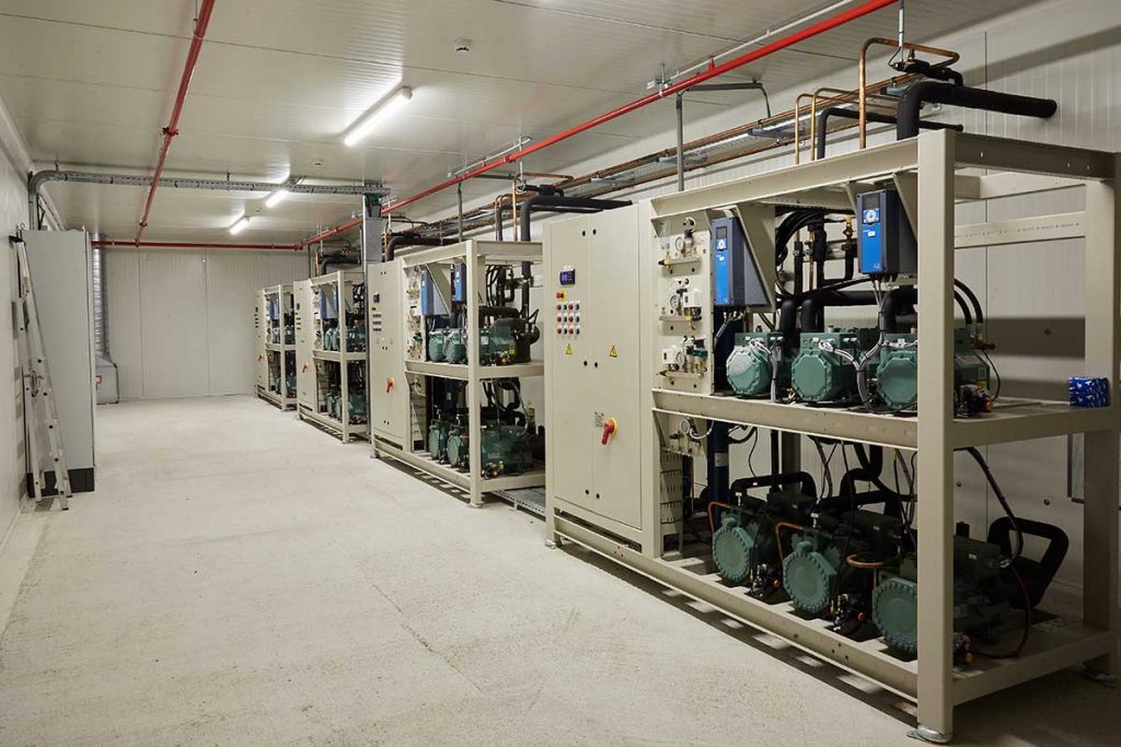 Industriële koelinstallatie met geavanceerde koeltechniek, inclusief compressoren en regelpanelen, in een technische ruimte. Efficiënte en duurzame koelsystemen voor industrie en commerciële toepassingen.